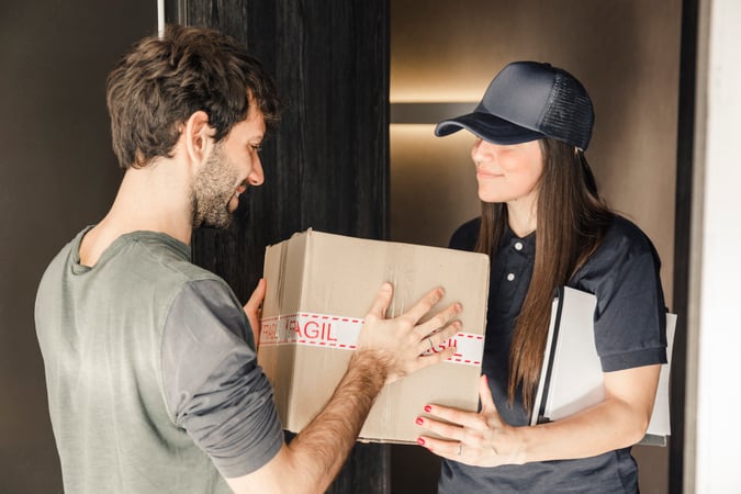 mensajero-mujer-joven-que-entrega-el-paquete-al-hombre-en-casa