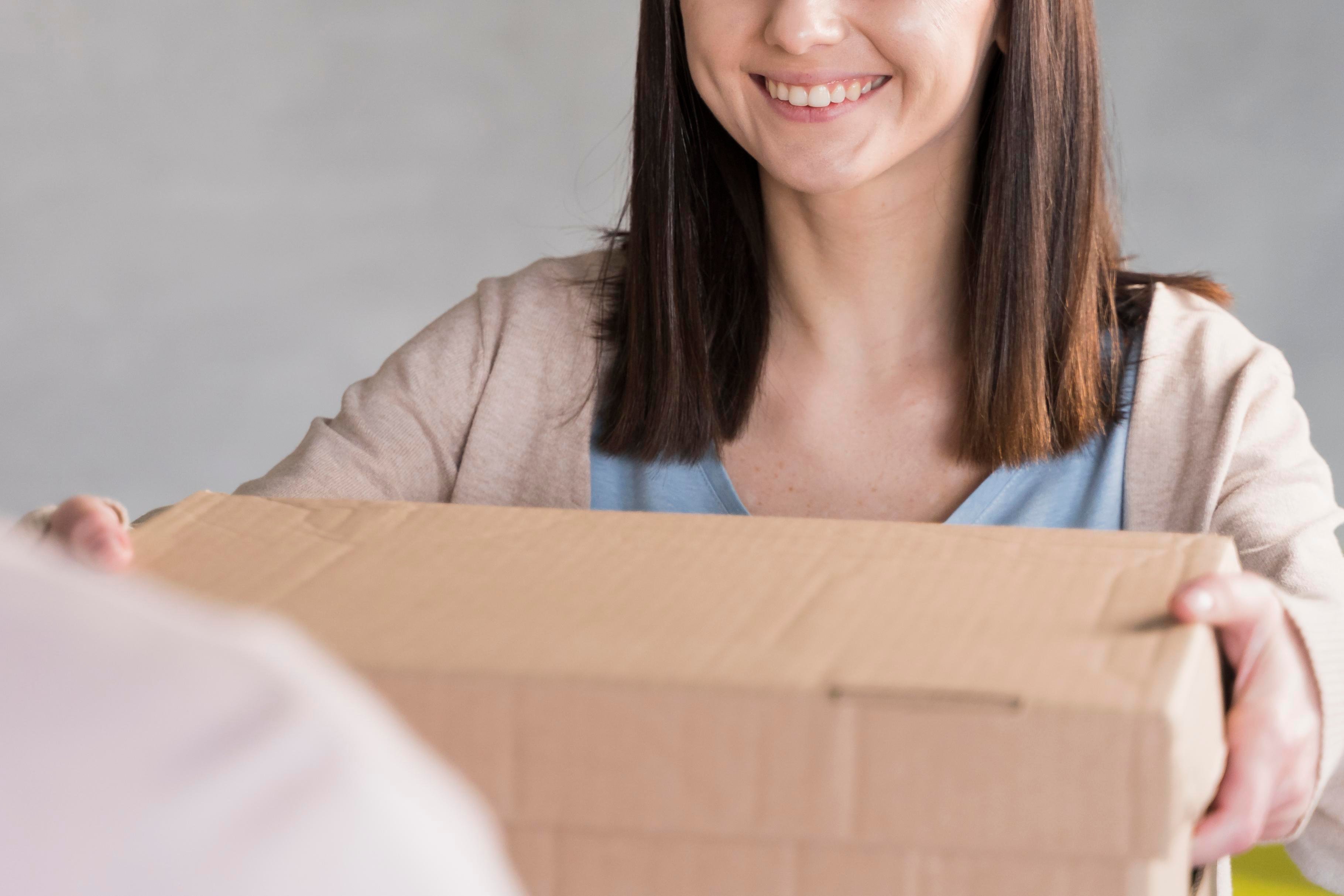 mujer-sonriente-entrega-caja-de-carton